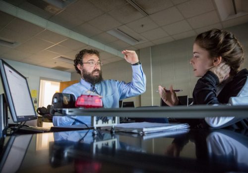 Professor James Perkins explaining a physics problem to a student during a lab.