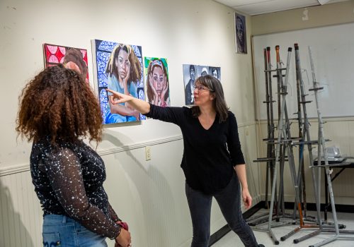 A professor pointing out part of a painting to a student.